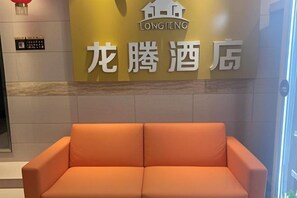 A reception area with a sofa and a wall displaying the hotel's name in Chinese characters.