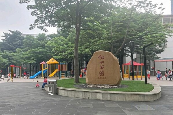 A playground with slides and climbing structures, surrounded by trees and a stone monument. - Longteng Boutique Hotel (Shenzhen Baoneng Center Sungang Subway Station Branch) (Shenzhen)