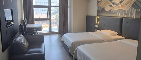 Una habitación de hotel con cama, sofá, escritorio y televisión.