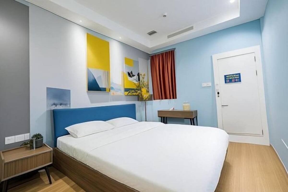Une chambre d’hôtel moderne dotée d’un grand lit, d’une table de chevet, d’une commode, d’un téléviseur fixé au mur et d’une porte avec une pancarte.