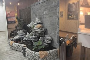 A reception area with a rock garden, a reception desk, and a wall-mounted sign. - Longteng Boutique Hotel (Shenzhen Baoneng Center Sungang Subway Station Branch) (Shenzhen)