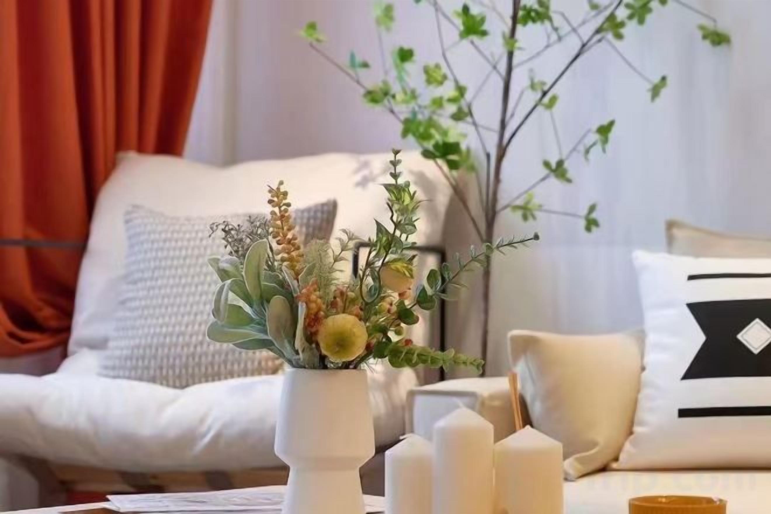 Un salon avec un canapé blanc, un vase décoratif rempli de fleurs et un chandelier.