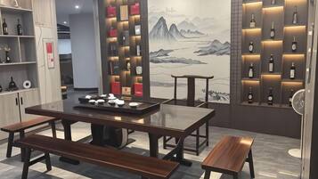 A restaurant with wooden tables and benches, shelves with bottles, and a mural on the wall.