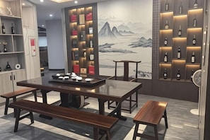 Un restaurant avec des tables et des bancs en bois, des étagères remplies de bouteilles et une fresque murale.