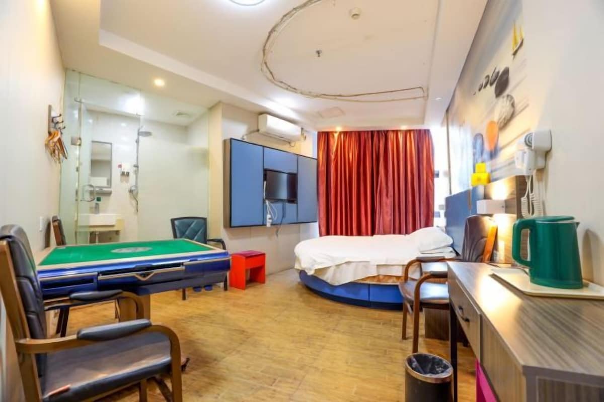 Une chambre d’hôtel avec un lit, un bureau, une chaise, une table de billard et une petite table avec une tasse.