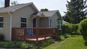 A two-story house with a front porch, a chimney, and a yard with greenery. - Pet-Friendly Family Home near Golf, LK MI, M22 (Arcadia)