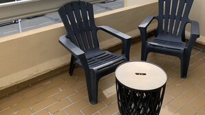A balcony with two black plastic chairs and a round table. - Solydays Floralies duplex for 6 people near the beach (Le Grau-du-Roi)