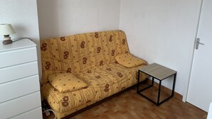 A small, furnished room with a sofa, a side table, and a lamp. - Solydays Floralies duplex for 6 people near the beach (Le Grau-du-Roi)