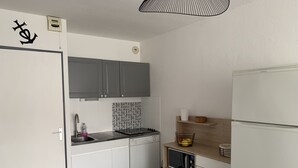 A compact kitchen with white cabinets, a built-in stove, and a wooden countertop. - Solydays Floralies duplex for 6 people near the beach (Le Grau-du-Roi)