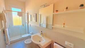 A bathroom with a shower, toilet, sink, and a mirror. - Appartamento Dante  (Prato)