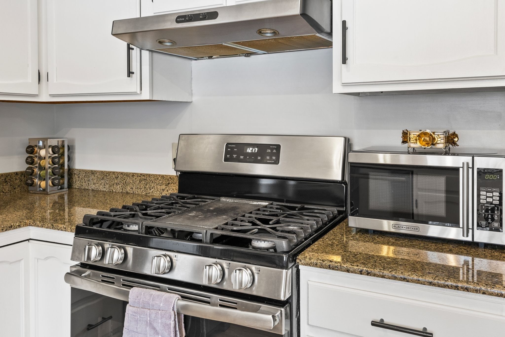 A kitchen with a stainless steel stove, a microwave, and a wine rack.