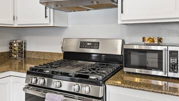 A kitchen with a stainless steel stove, a microwave, and a wine rack.