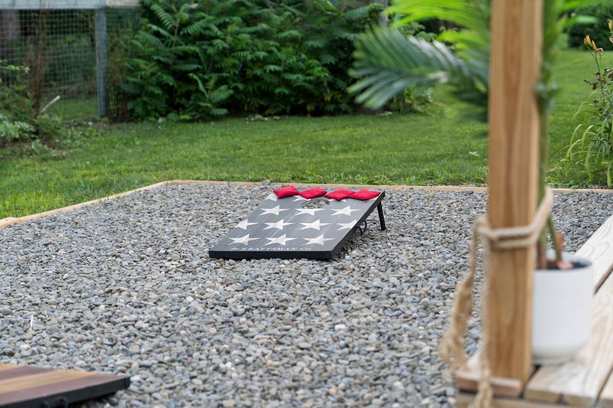 Un espace extérieur rectangulaire aménagé avec des sièges, une table ornée d’un motif en étoile et des coussins rouges.