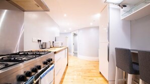 Une cuisine moderne équipée d’une cuisinière à gaz, d’un four et de meubles blancs.