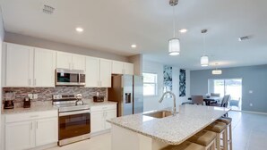 A modern kitchen with white cabinets, stainless steel appliances, and a granite countertop. - Palm Breeze Lux Stay - Port St. Lucie (Port Saint Lucie)