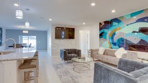 A spacious living area with a modern kitchen, a large abstract painting, and a comfortable seating arrangement. - Palm Breeze Lux Stay - Port St. Lucie (Port Saint Lucie)