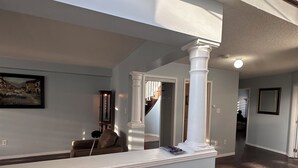 A spacious hallway with a high ceiling, a staircase with a dark wooden finish, and a light blue wall with a framed picture. - Sophisticated 2-Story Classic Home (Brampton)