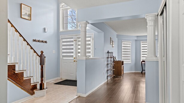 A spacious hallway with a wooden staircase, light blue walls, and a large window. - Sophisticated 2-Story Classic Home (Brampton)