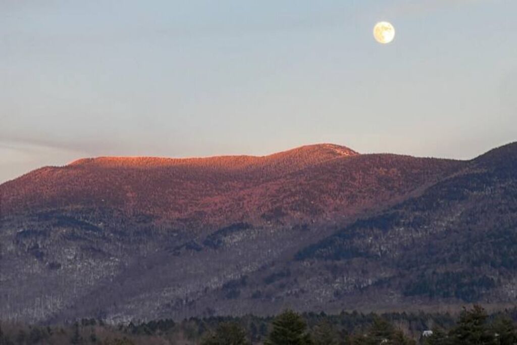 Un paysage de montagne avec une lune visible dans le ciel.