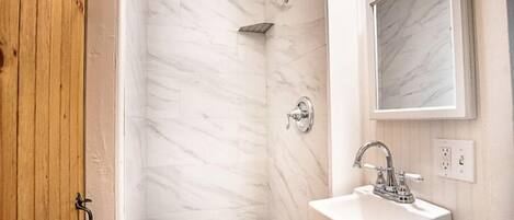 A bathroom with a shower, a sink, and a mirror.