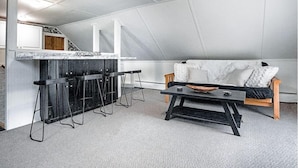 A loft-style living space with a kitchen area, a sofa, and a coffee table. - The Cider Loft (Waterbury)