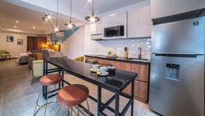 Cocina moderna con isla central, electrodomésticos de acero inoxidable, iluminación colgante y un dispensador de agua a la vista.
