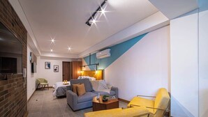 Una sala de estar moderna con un sofá, un sillón y una mesa de centro. Hay una chimenea y un televisor montado en la pared.