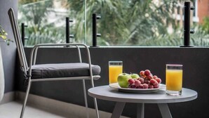 Un balcón con una mesa dispuesta para el desayuno, que incluye frutas y jugo, y una silla.