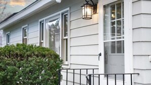 A house with a white exterior, a black metal railing, and a window with a white door.