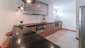 A modern kitchen with a black granite countertop, stainless steel appliances, and pendant lighting. - E201 - Spacious 2-bed / 2-bath, A/C & Fast WiFi (Cali)