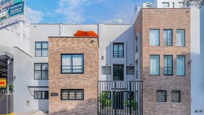 A modern building with a brick facade, multiple windows, and a gated entrance. - E103 - Brand-New Quiet & Comfortable Studio Unit (Cali)