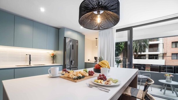 Une cuisine moderne dotée d’un îlot central, d’un réfrigérateur en acier inoxydable et d’un luminaire suspendu.