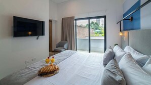 A modern hotel room with a large bed, a flat-screen TV, a balcony with a view, and a breakfast setup on the bed. - E302 - Luxurious Top Floor Apartment with Terrace (Cali)