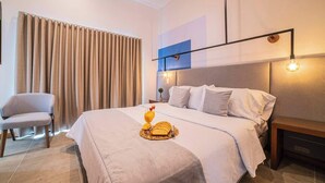A hotel room with a bed, a chair, a bedside table, and a wall-mounted light fixture. - E302 - Luxurious Top Floor Apartment with Terrace (Cali)