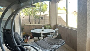 A covered patio area with a hanging chair, a table, and chairs. - 2-bedroom clean home in Sierra Vista, WiFi, AC, covered patio & shaded backyard. (Sierra Vista)