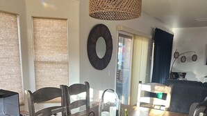 A dining area with a wooden table, chairs, a woven pendant light, and a decorative mirror on the wall. - 2-bedroom clean home in Sierra Vista, WiFi, AC, covered patio & shaded backyard. (Sierra Vista)