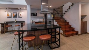 Eine moderne Küche mit Kochinsel, Barhocker, einer Treppe und einer Mikrowelle.