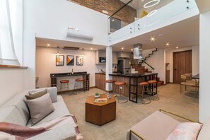 A spacious living area with a sofa, coffee table, and a kitchen in the background. - E104 - Fantastic Two Story 3-bed / 3-bath Unit (Cali)