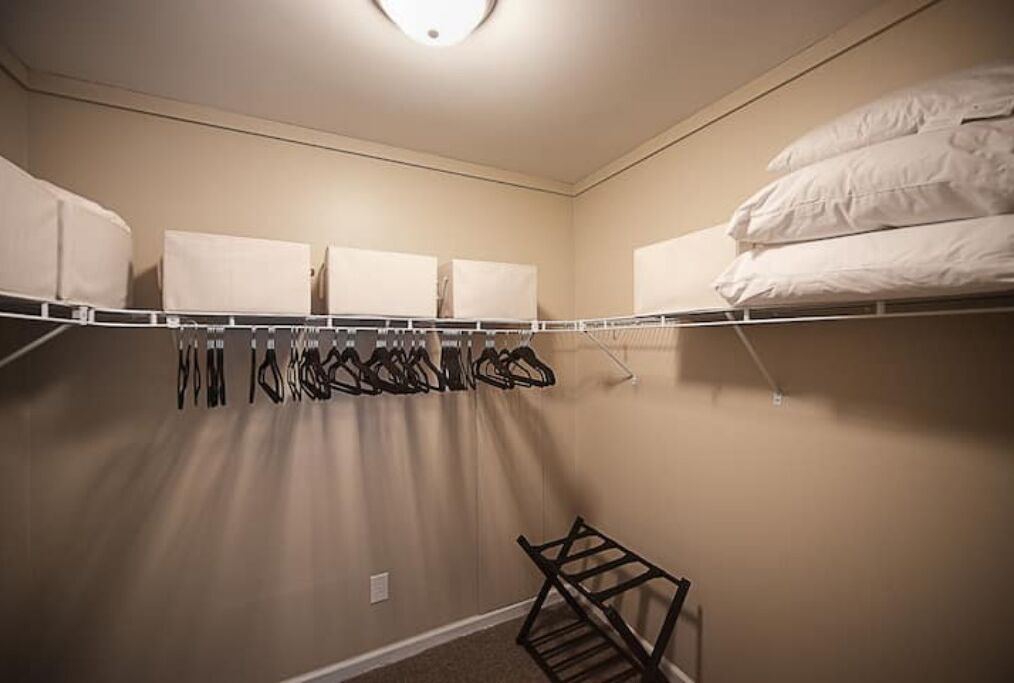 A bedroom with a bunk bed, a closet with hanging clothes, and a small shelf.