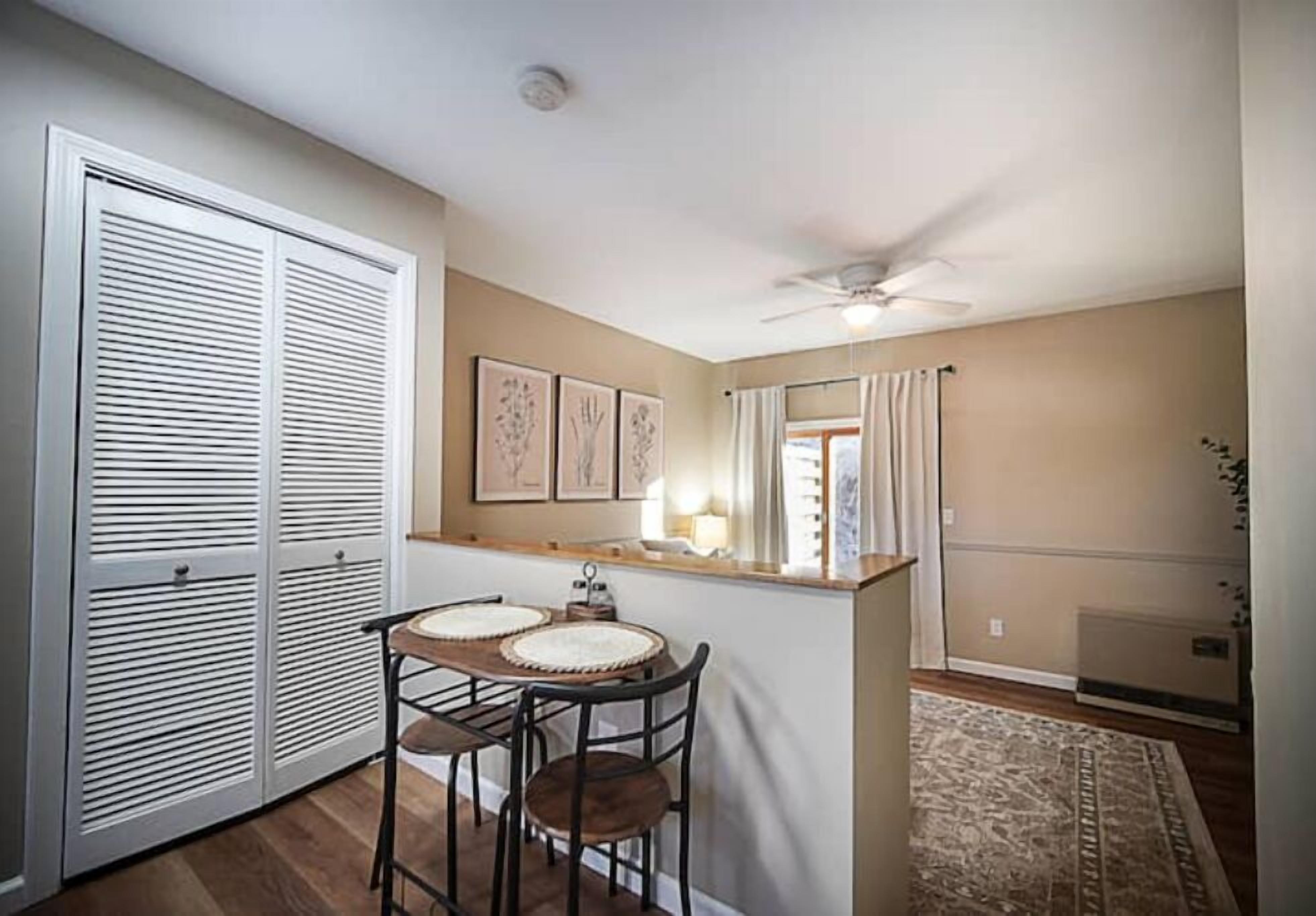 Una cocina compacta con comedor, ventilador de techo y vistas al exterior por una ventana.