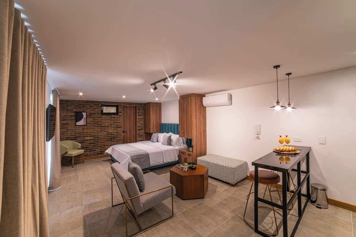 Una habitación de hotel moderna con una cama, un pequeño sofá, una mesa de comedor y una kitchenette.
