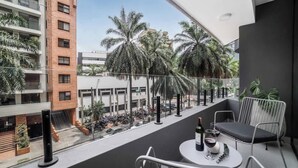 A balcony with a table set for two, a bottle of wine, and a glass. There are chairs and a potted plant. - Hygge 301 - 2-Bed Beauty | Balcony | Near Granada (Cali)