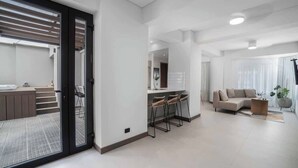 Un salon moderne avec un canapé, une table basse et un coin bar équipé de tabourets.