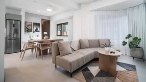 A modern living room with a sofa, coffee table, and dining area.