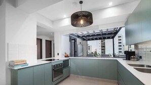 Une cuisine moderne dotée d’un îlot central, d’un four encastré et d’un luminaire suspendu.