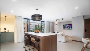 Una cocina moderna con una isla central, taburetes de bar y un amplio ventanal.