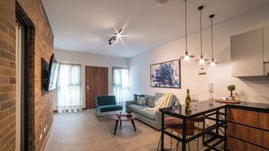 A modern living room with a sofa, a coffee table, and a dining area with a bar. - Luxury 3-Bed | Walk to Boulevar & Granada | E101 (Cali)
