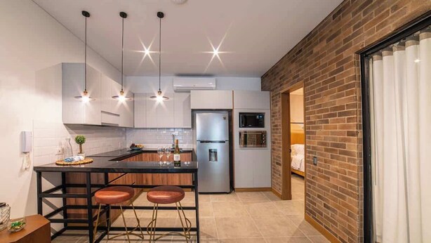 A modern kitchen with a central island, bar stools, stainless steel appliances, and pendant lighting. - Luxury 3-Bed | Walk to Boulevar & Granada | E101 (Cali)