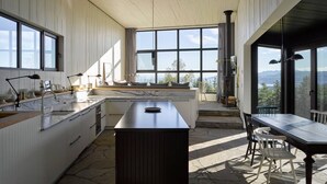 Eine moderne Küche mit einer großen Kochinsel, integrierten Geräten und großen Fenstern mit Blick ins Freie.