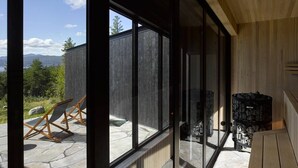 Ein modernes Interieur mit großen Fenstern, Steinböden und einem Kamin.